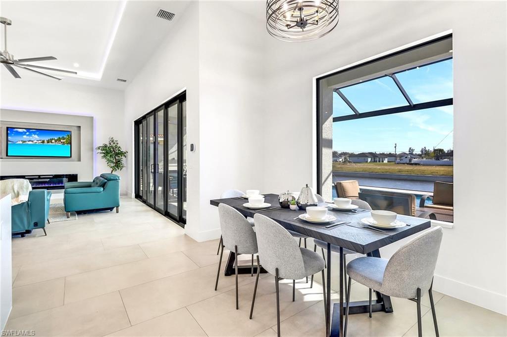 Open-concept dining area featuring a prominent window, a rectangular dark-finish dining table, and light-tone tile flooring