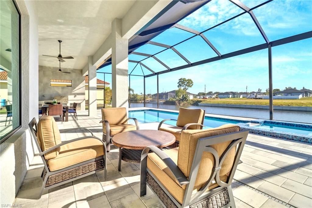 Screened lanai featuring a swimming pool, integrated spa with mosaic tile, and a built-in outdoor kitchen with grill