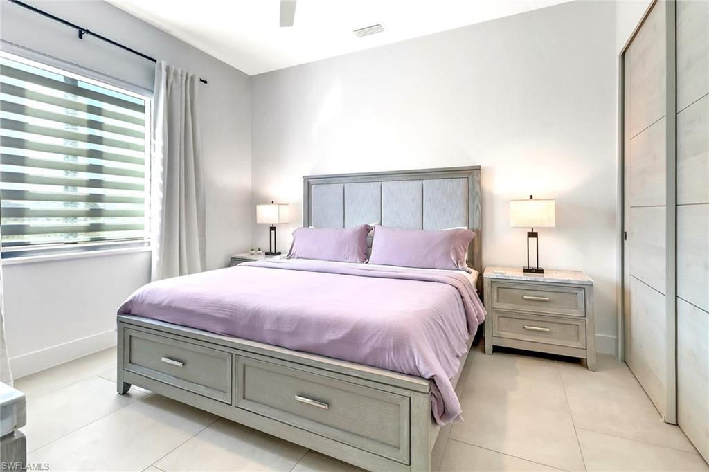 Spacious bedroom with light-toned tile flooring and a ceiling fan