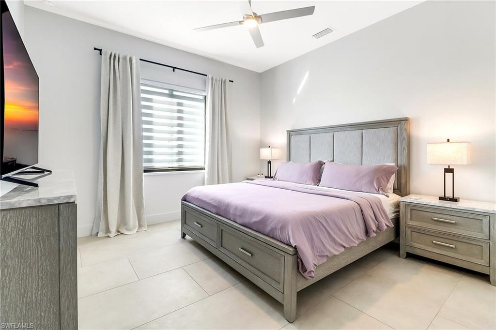 Room with light-toned tile flooring, featuring a large window with blinds and drapes