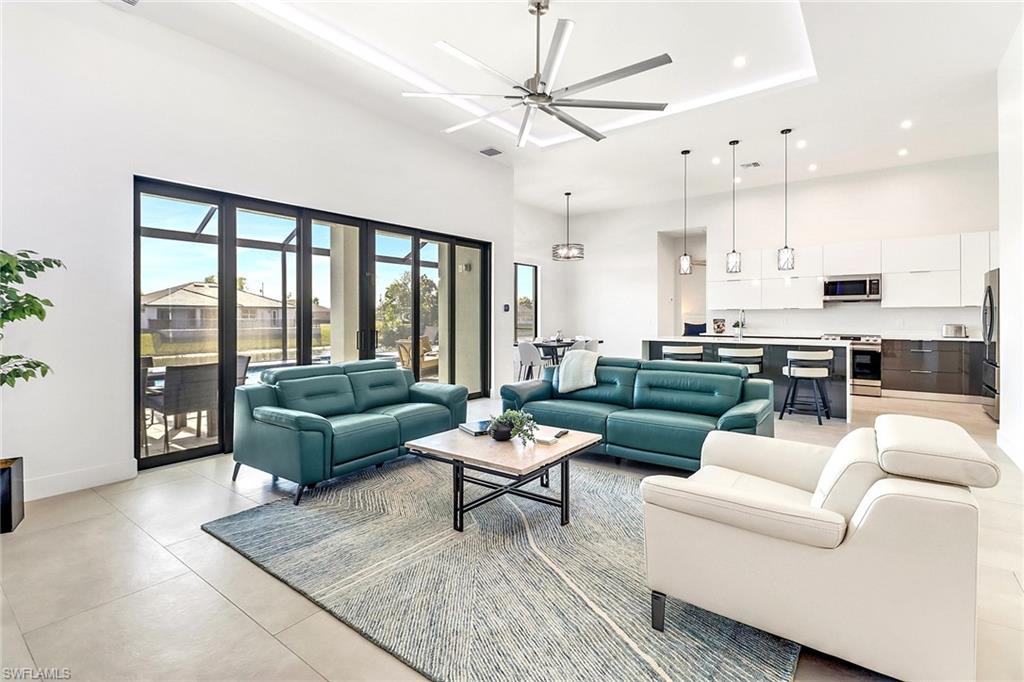 Spacious open-concept living area featuring a modern kitchen, high ceilings with recessed lighting, and large sliding glass doors opening to outdoor patio space