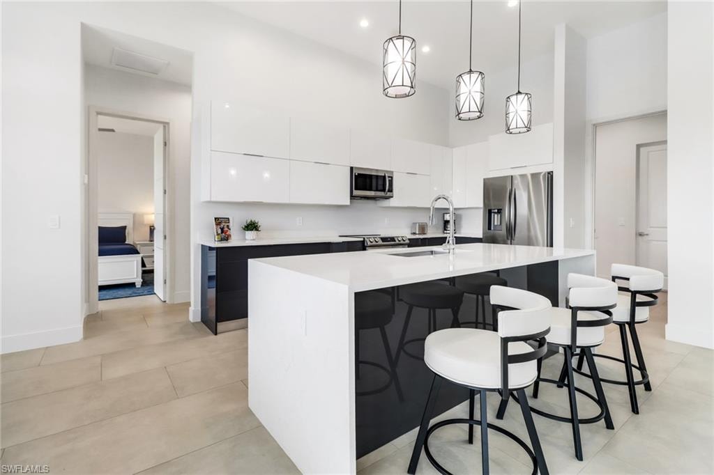 Contemporary kitchen featuring a waterfall island with a white countertop and dark base cabinetry