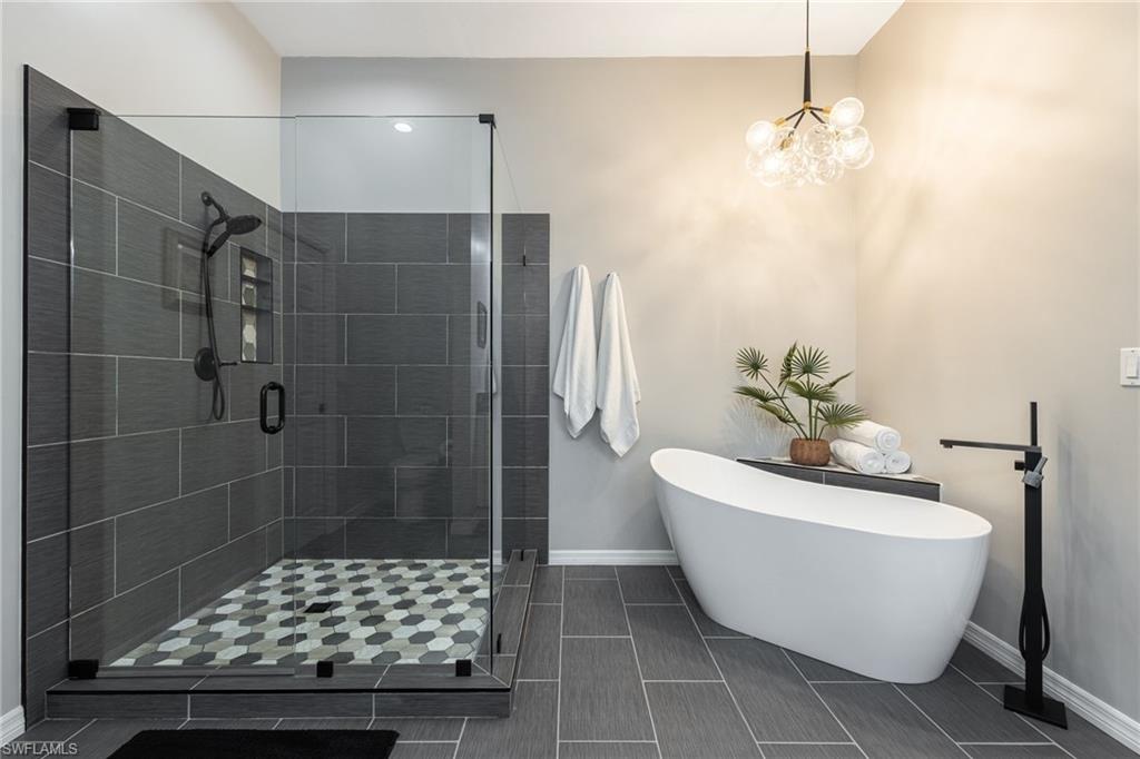 Fully renovated bathroom with glassed in tiled shower, soaking tub. Check out that chandelier!