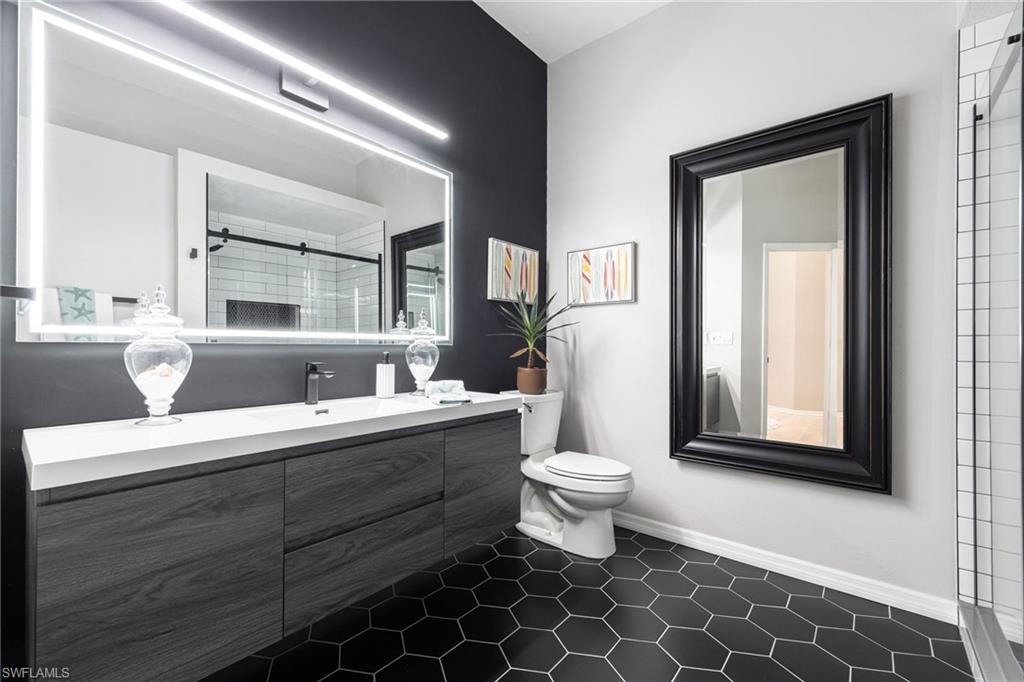 This is gorgeous renovated bathroom. Floating vanity, tiled flooring, electric light, contemporary style.
