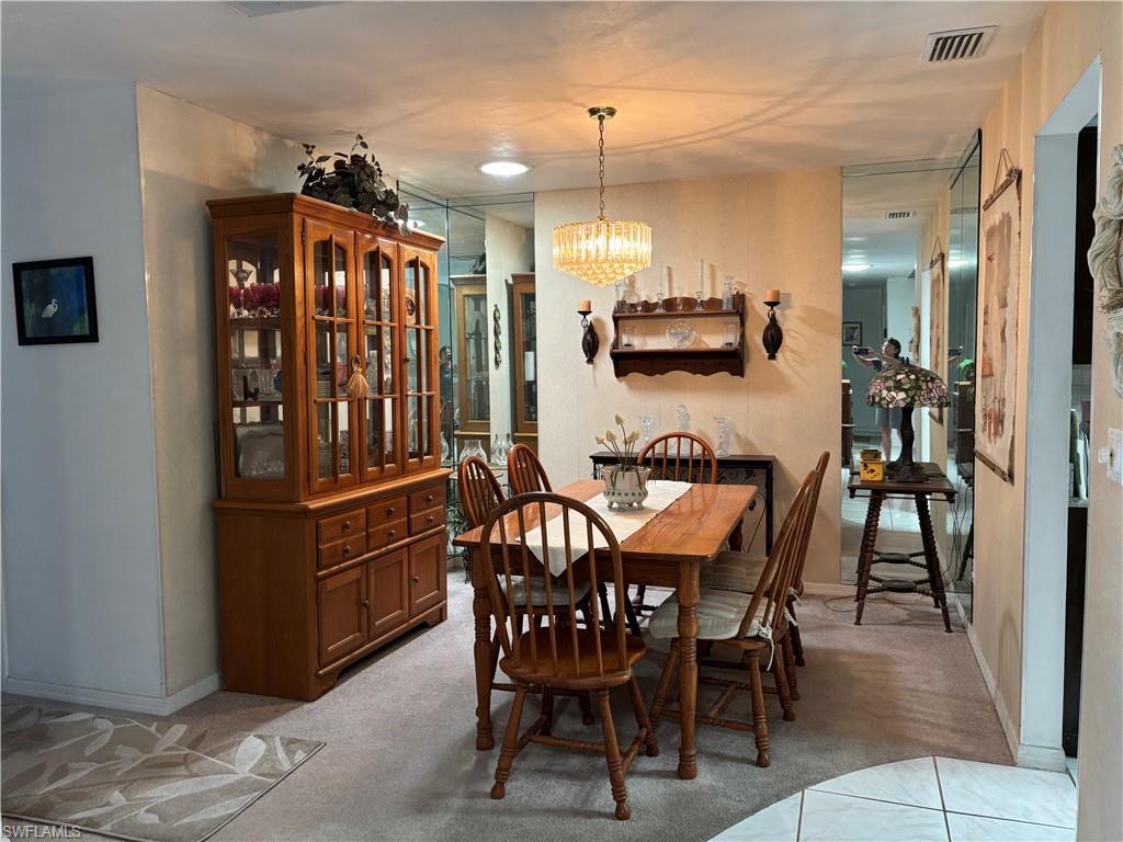 Dining area featuring a central chandelier, wall-mounted shelving with sconces, and full-height mirrored wall panels