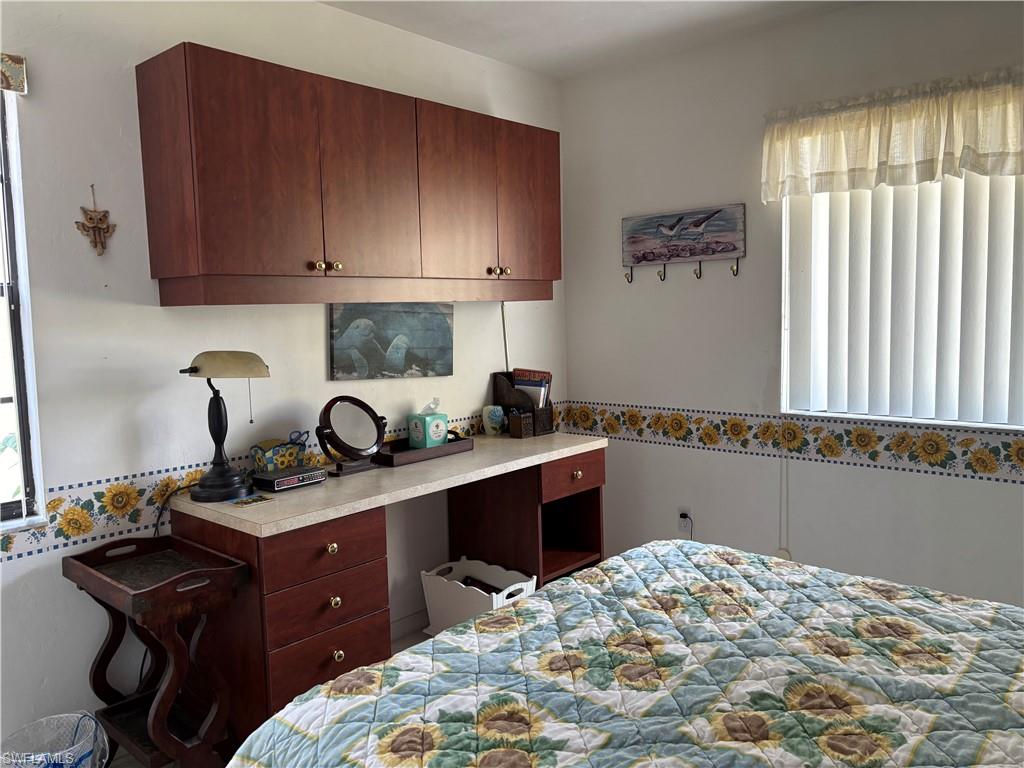 Built-in desk area featuring wood-finish cabinetry, a light-colored countertop, and a window with vertical blinds