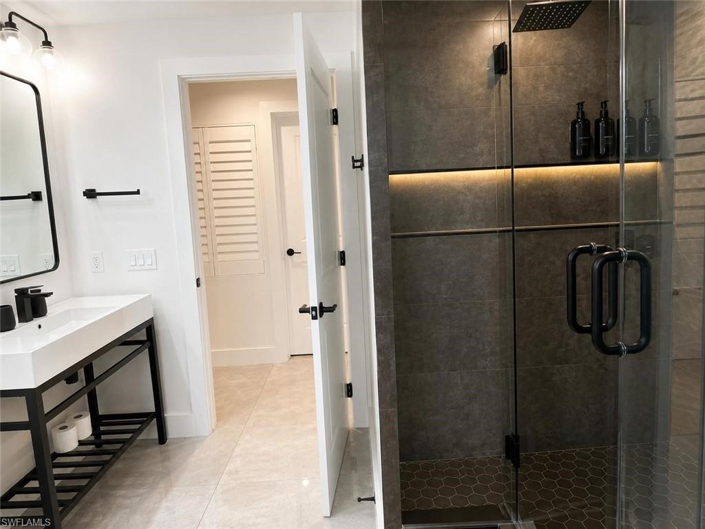 Contemporary bathroom featuring a frameless glass shower enclosure, dark grey large format tile surround, and a rain showerhead