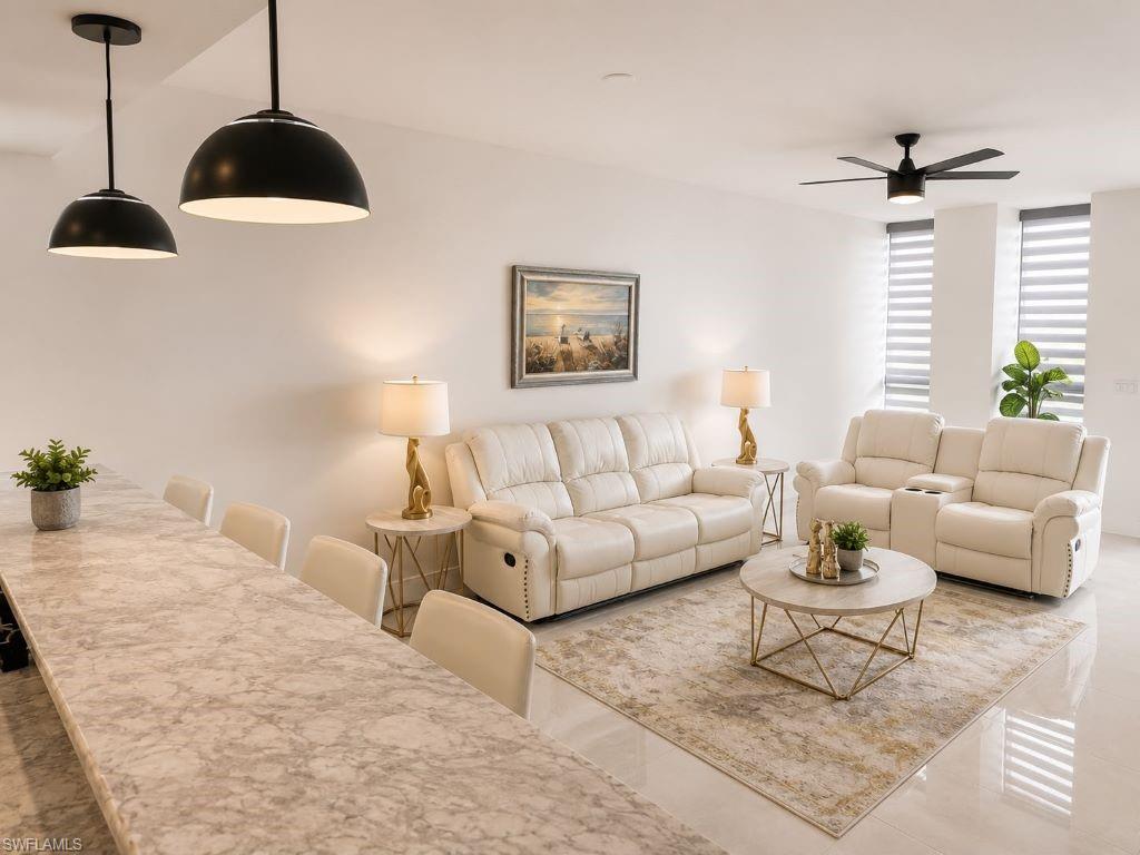 Open-concept living space featuring a long countertop with seating, two pendant lights, and a ceiling fan
