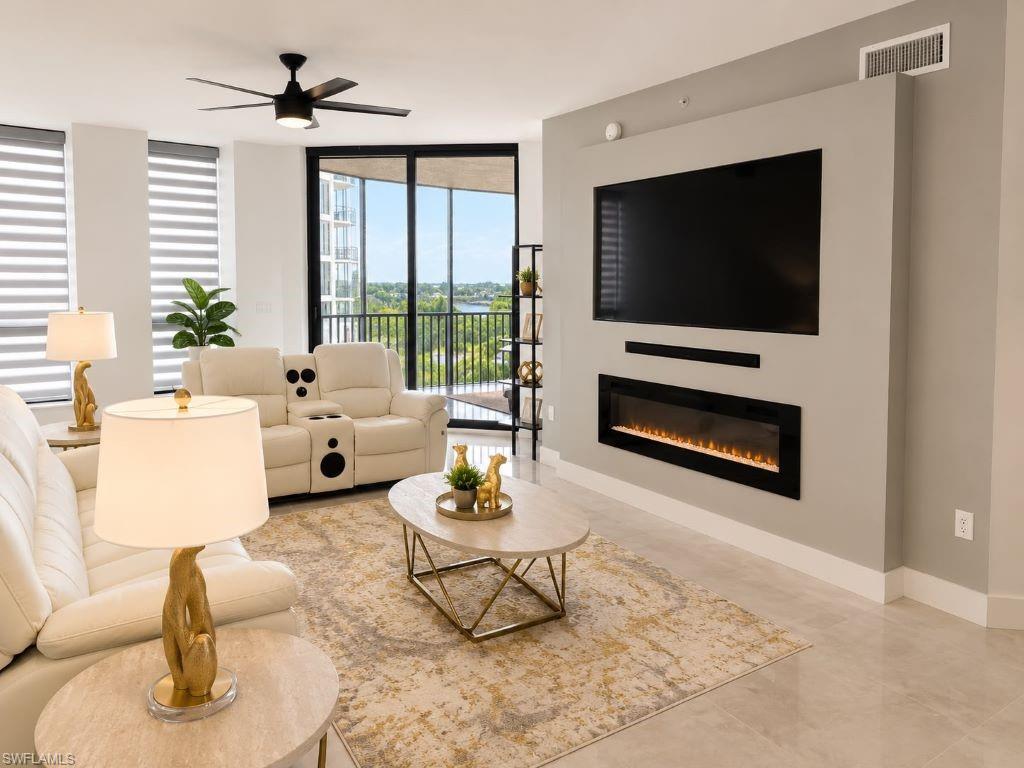 Spacious living area featuring floor-to-ceiling sliding glass doors, an integrated linear electric fireplace, and a contemporary ceiling fan