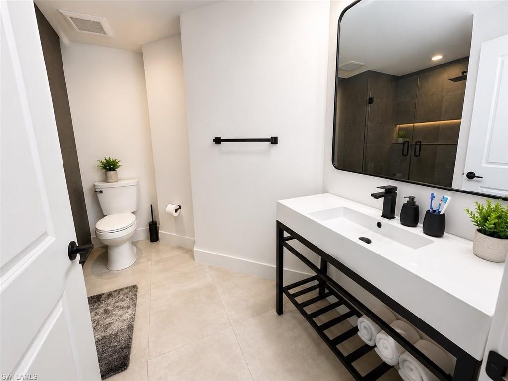 Contemporary bathroom featuring a black-framed vanity with integrated sink, matte black hardware, and an oversized mirror
