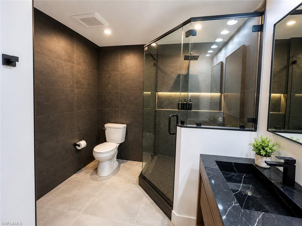 Modern bathroom featuring a glass-enclosed shower with a rainfall showerhead, integrated linear lighting, and a built-in niche