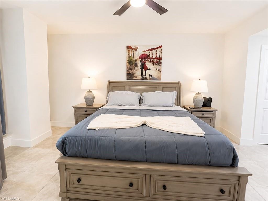 Bedroom featuring a ceiling fan with integrated lighting, tile flooring, and a paneled door