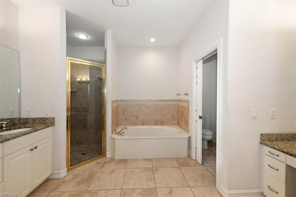 Bathroom featuring vanity, a shower stall, tile patterned flooring, toilet, and a bath