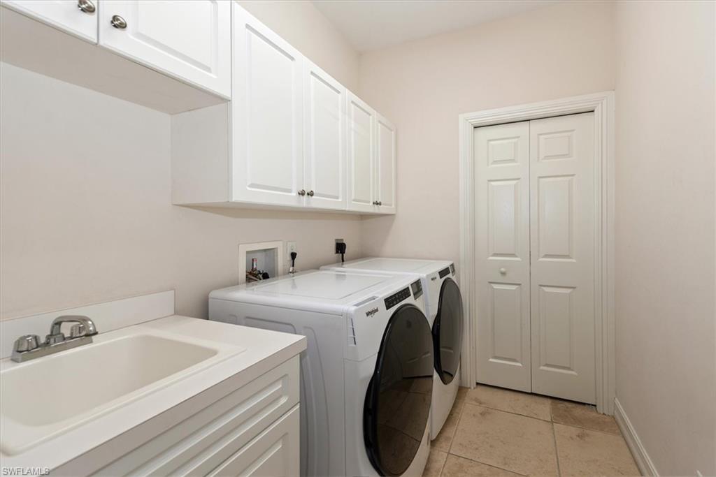 Laundry area with cabinet space, washer and dryer, light tile patterned flooring, and baseboards