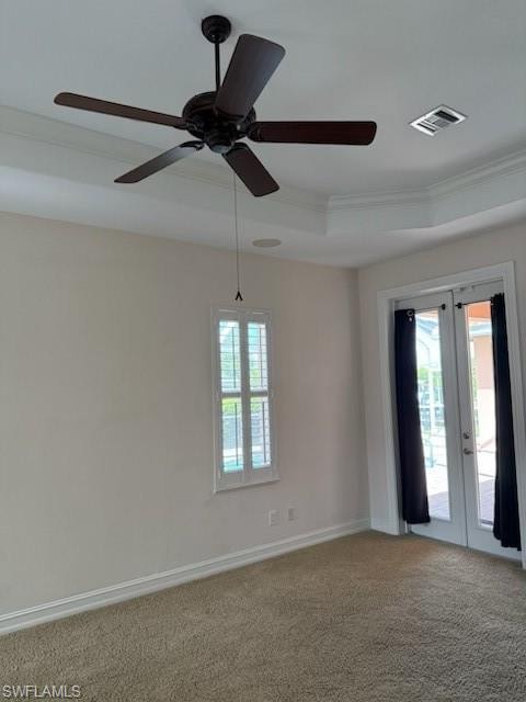 Carpeted empty room with crown molding, french doors, ceiling fan, baseboards, and a raised ceiling