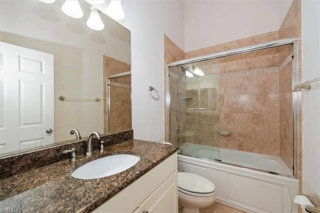 Bathroom with toilet, combined bath / shower with glass door, and vanity