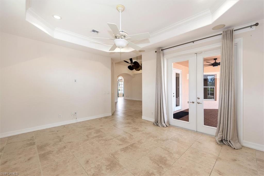 Empty room with a tray ceiling, french doors, ceiling fan, crown molding, and recessed lighting