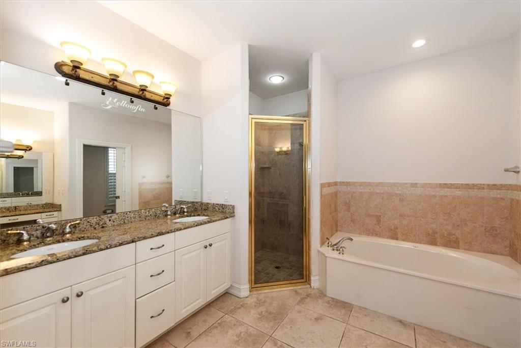 Bathroom featuring tile patterned flooring, a stall shower, a garden tub, and double vanity