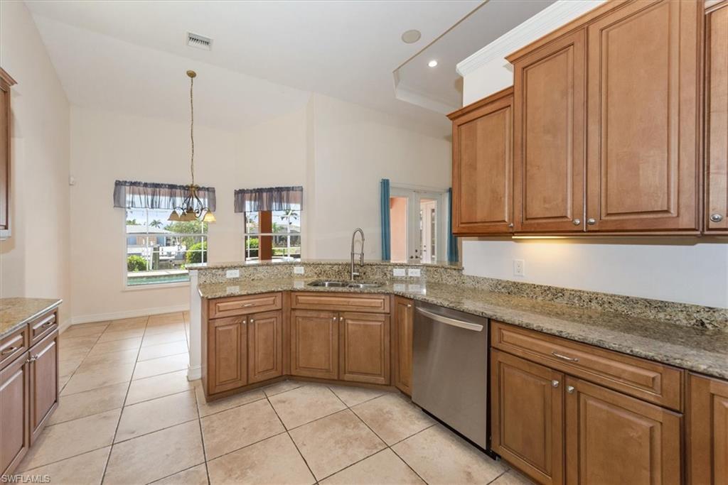 Kitchen featuring dishwasher, a peninsula, a sink, brown cabinets, and light tile patterned flooring