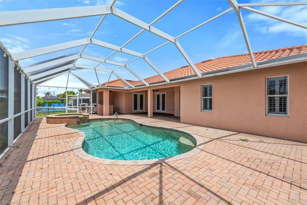 View of pool featuring a pool with connected hot tub, a patio area, and a lanai