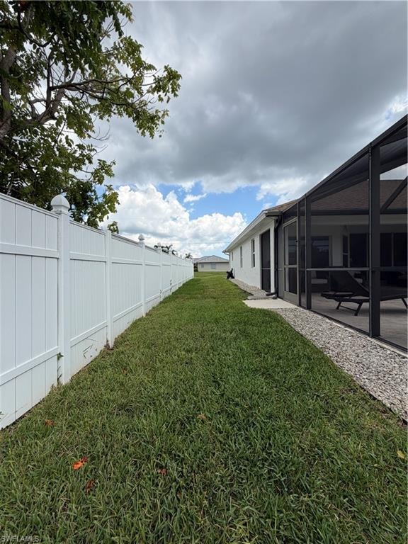 Private side yard space featuring a white privacy fence, screened lanai, and a gravel perimeter alongside the home