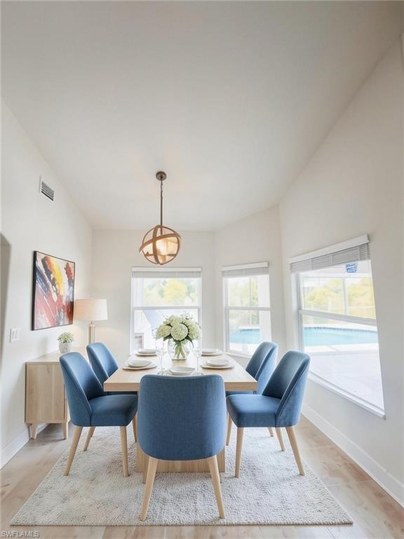 Dining area featuring a vaulted ceiling and wood-finish flooring