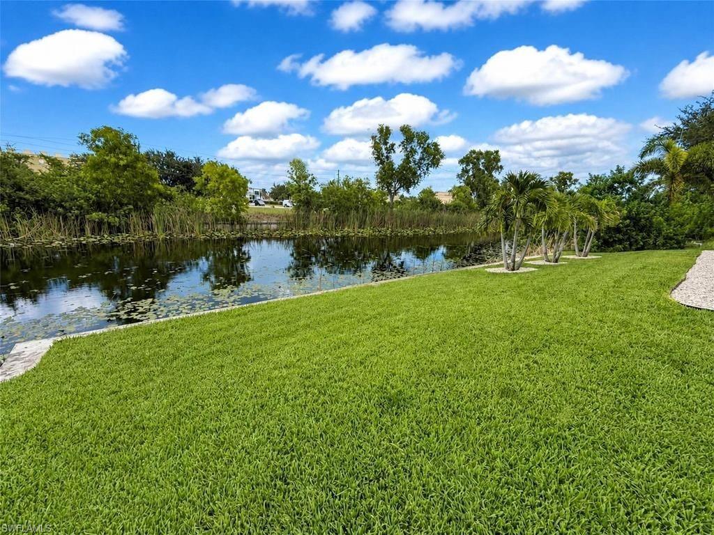 Expansive green lawn bordering a tranquil canal with lily pads and dense foliage