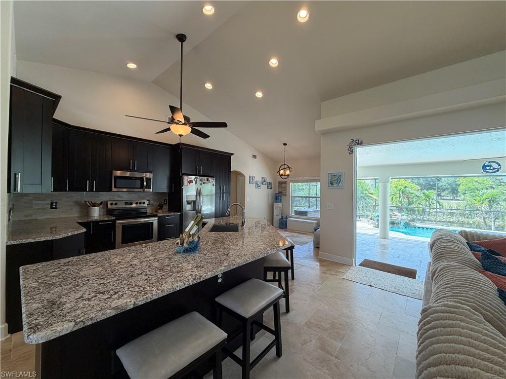 Kitchen featuring dark wood cabinetry, stainless steel appliances, and a generously sized island with a light-toned granite countertop