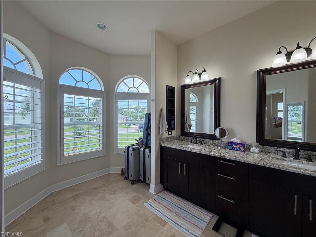 Bathroom featuring a dual vanity with dark wood cabinetry, granite-finish countertops, and rectangular framed mirrors