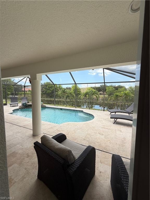 Nice covered seating area from Primary Bedroom Expansive screened lanai featuring a curved swimming pool, a water feature, and a paved deck
