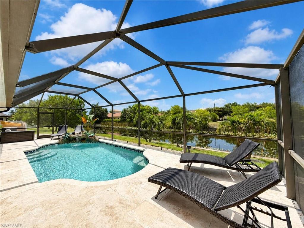 Screened lanai featuring a freeform pool with a rock waterfall