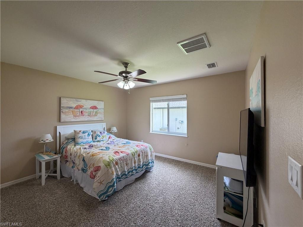 Bedroom 2 with textured carpet flooring, a window featuring horizontal blinds, and a ceiling fan with integrated lighting
