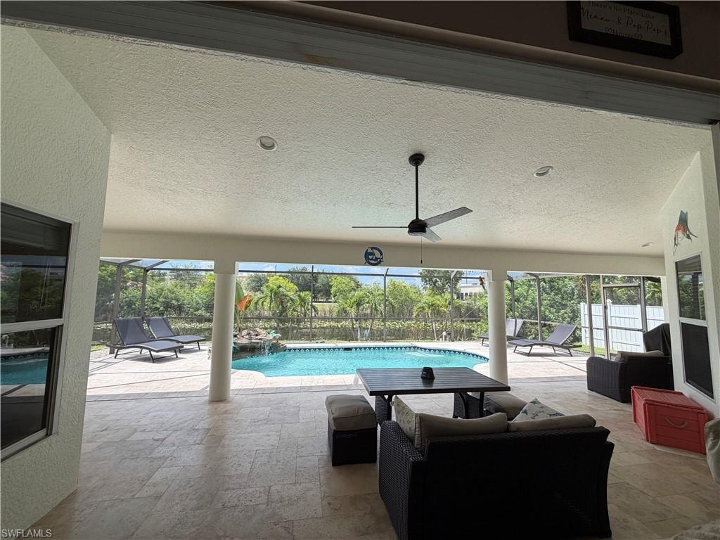 Expansive screened lanai featuring a ceiling fan, recessed lighting, and travertine tiled flooring
