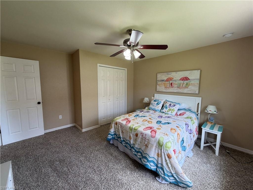 Bedroom 2 with Carpeted flooring, featuring a white paneled door with black hardware, a ceiling fan with integrated lighting, and white bi-fold closet doors