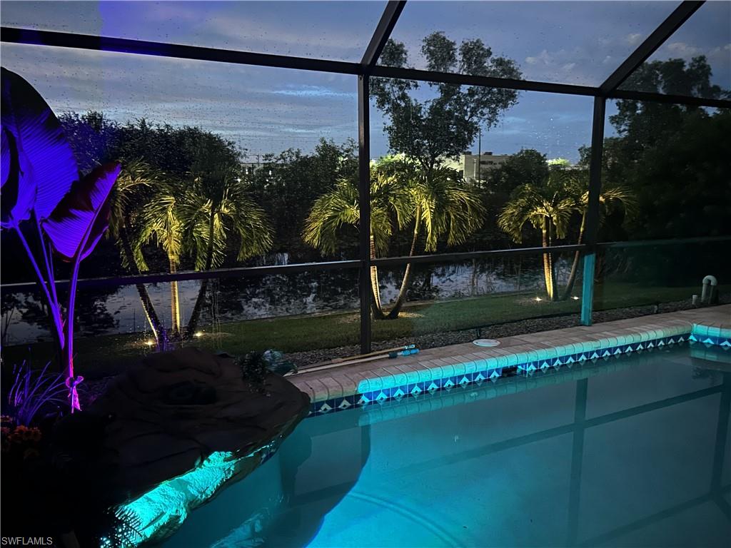 Awesome lighting inside Screened swimming pool with beautiful tile border and a rock-feature waterfall
