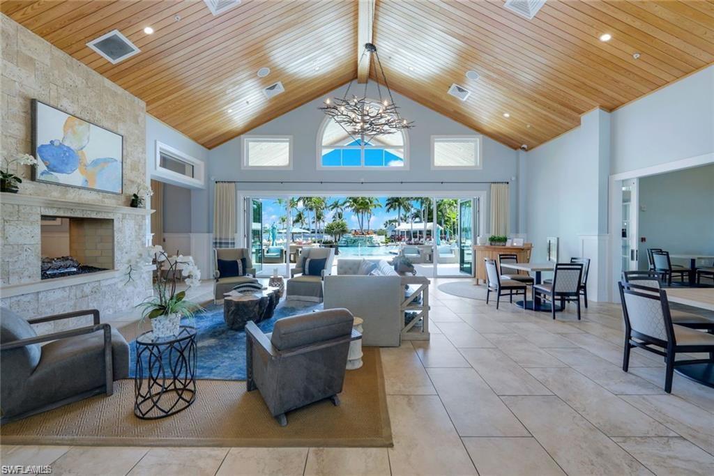 Living room with wooden ceiling, beam ceiling, a notable chandelier, and a towering ceiling
