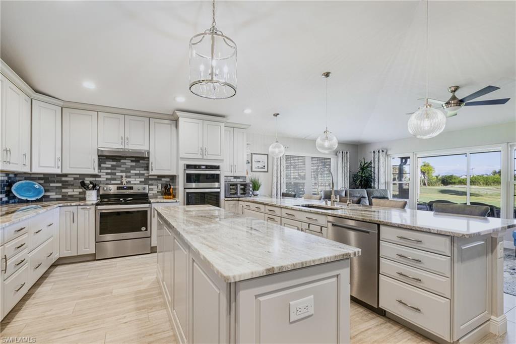 Spacious kitchen featuring an expansive center island, light-toned cabinetry, stainless steel appliances, and wood-finish flooring