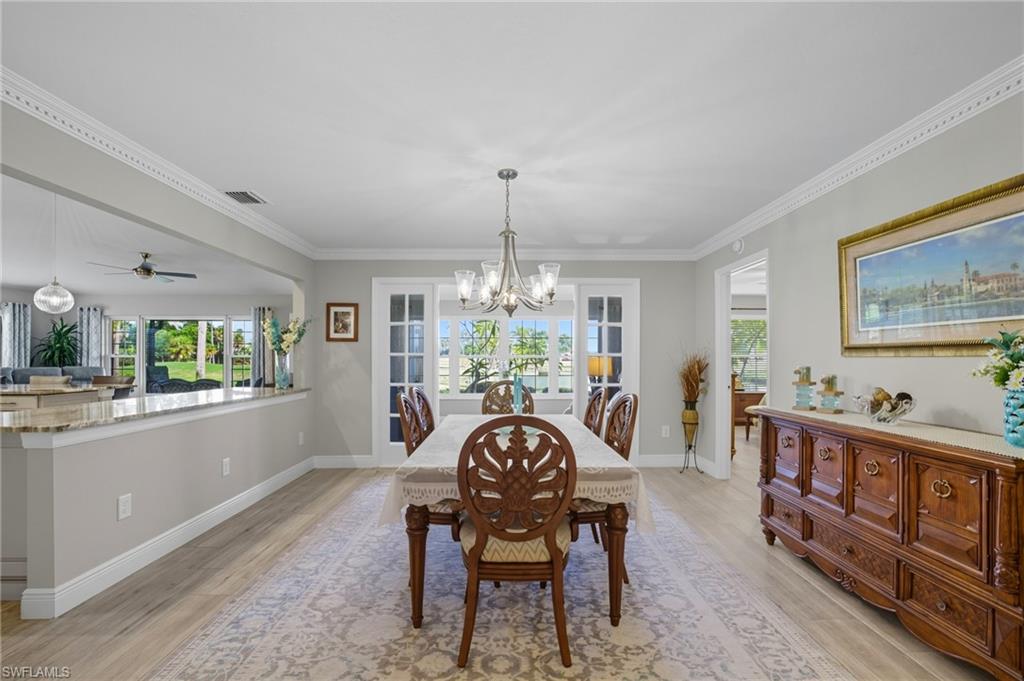 Dining area featuring wood-finish flooring, crown molding, and a chandelier