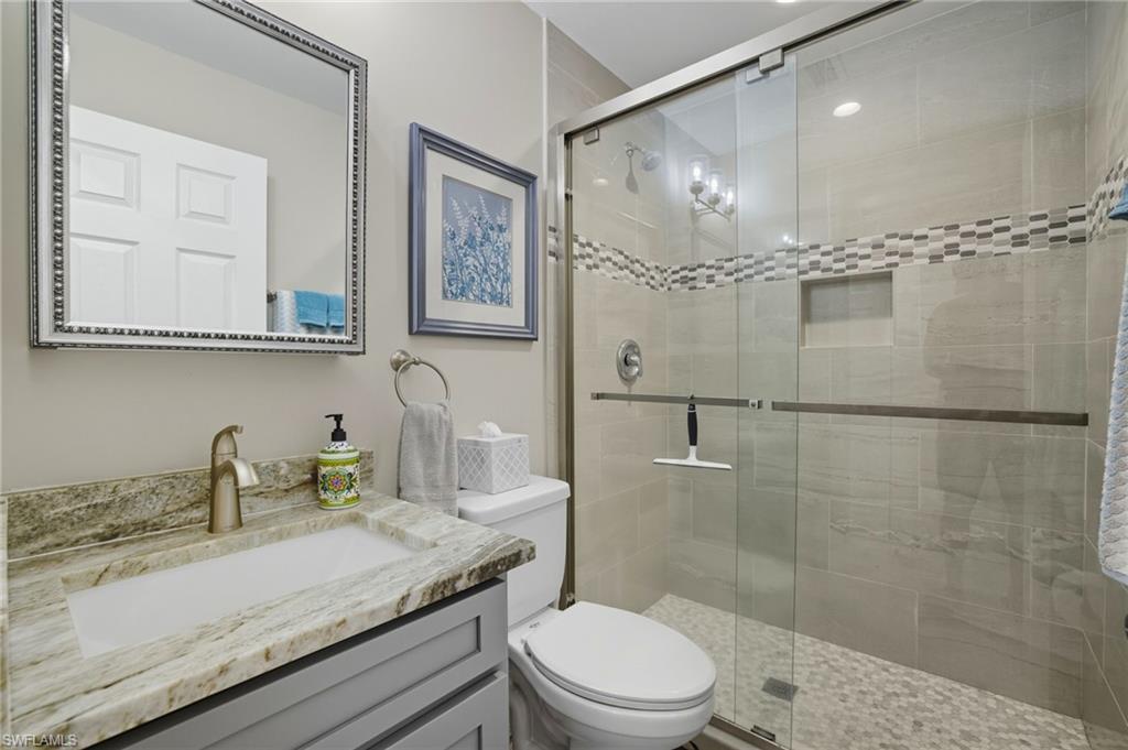 Bathroom with a gray vanity, integrated sink, and stone-finish countertop