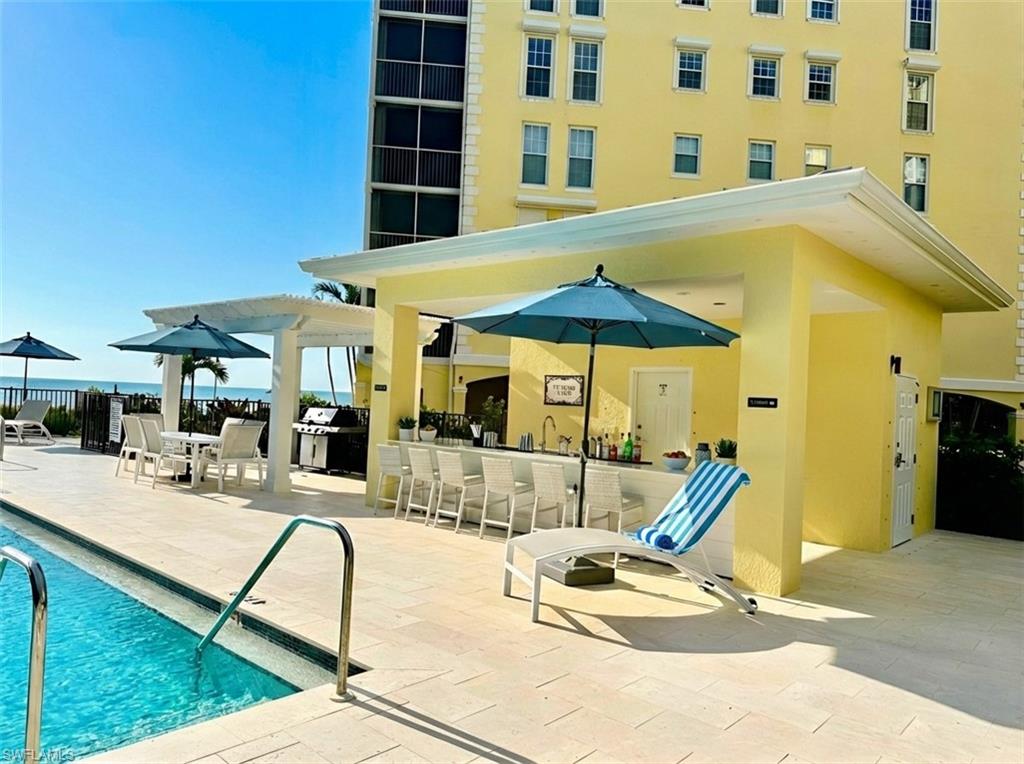 Community pool featuring area for grilling, an outdoor bar and dining area, and a patio