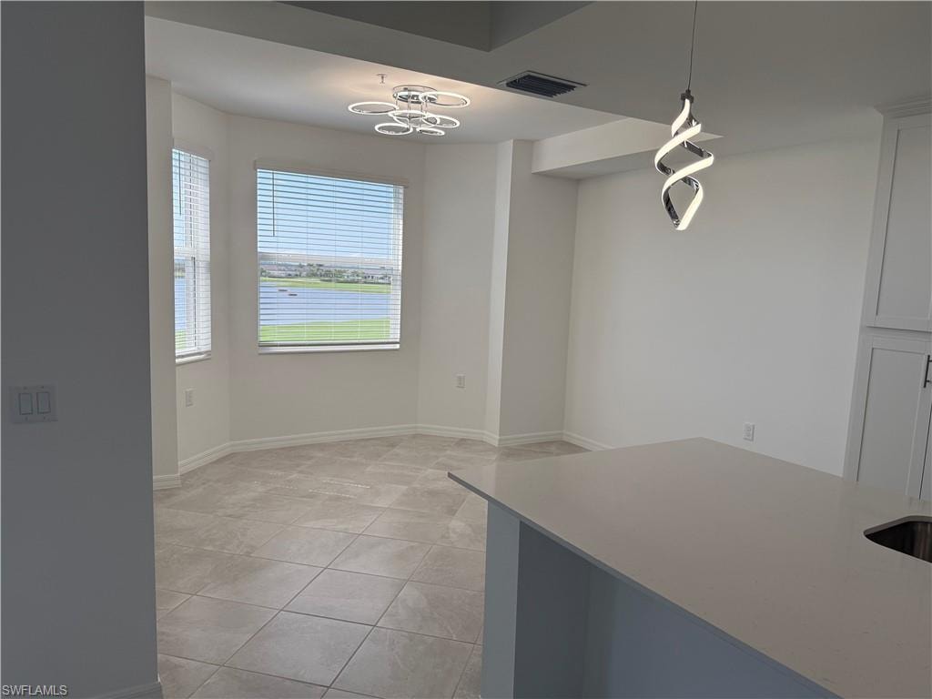 Light-filled dining area featuring bay windows, modern tile flooring, and a contemporary ceiling fixture