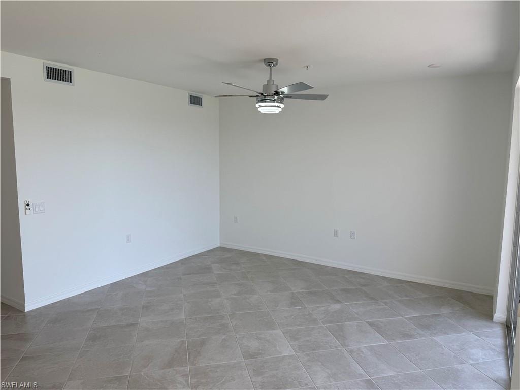 Spacious interior featuring neutral tone tile flooring, a modern ceiling fan with integrated lighting, recessed lighting, white baseboards, and a large sliding door opening to the exterior