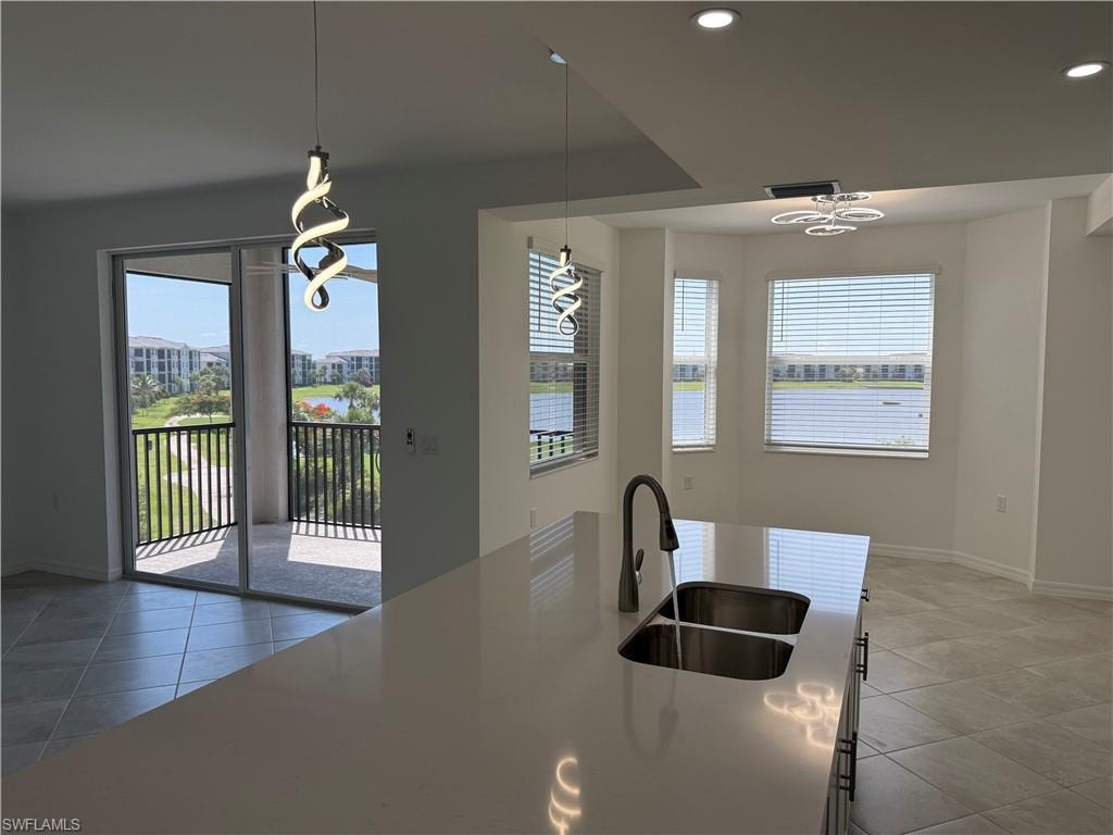 View from modern kitchen island featuring a double stainless steel sink, gooseneck faucet, and light-toned solid surface countertop
