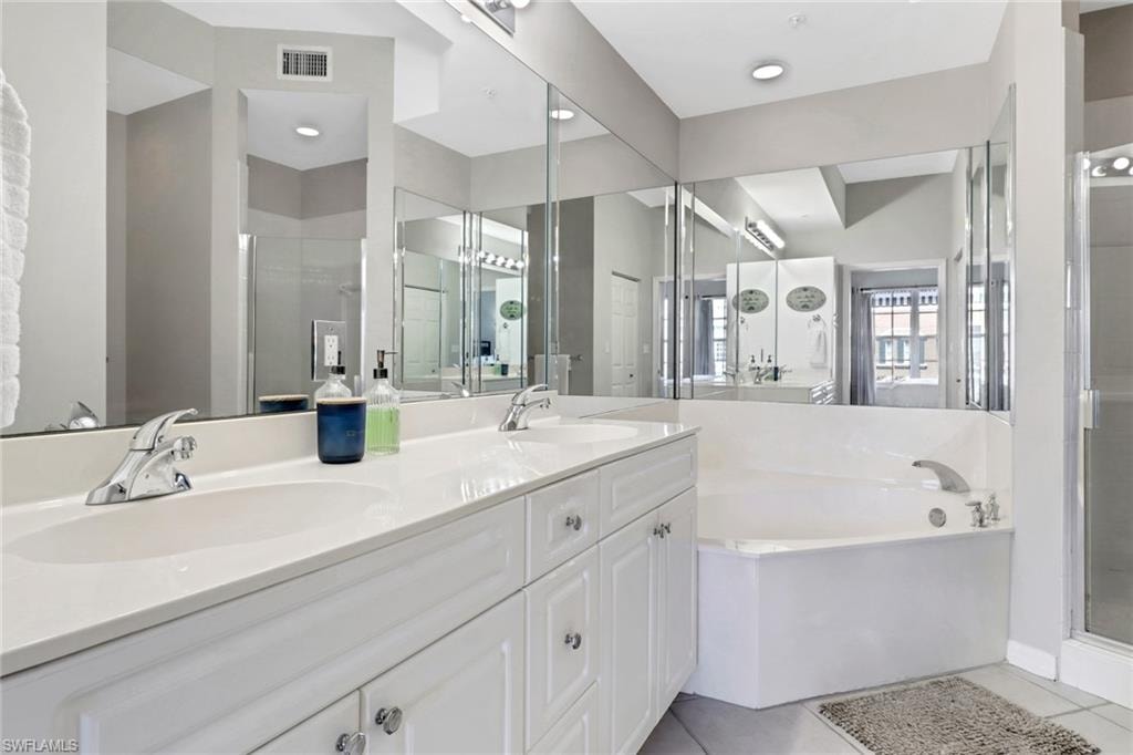 Full bath featuring a bath, double vanity, a shower stall, and tile patterned flooring