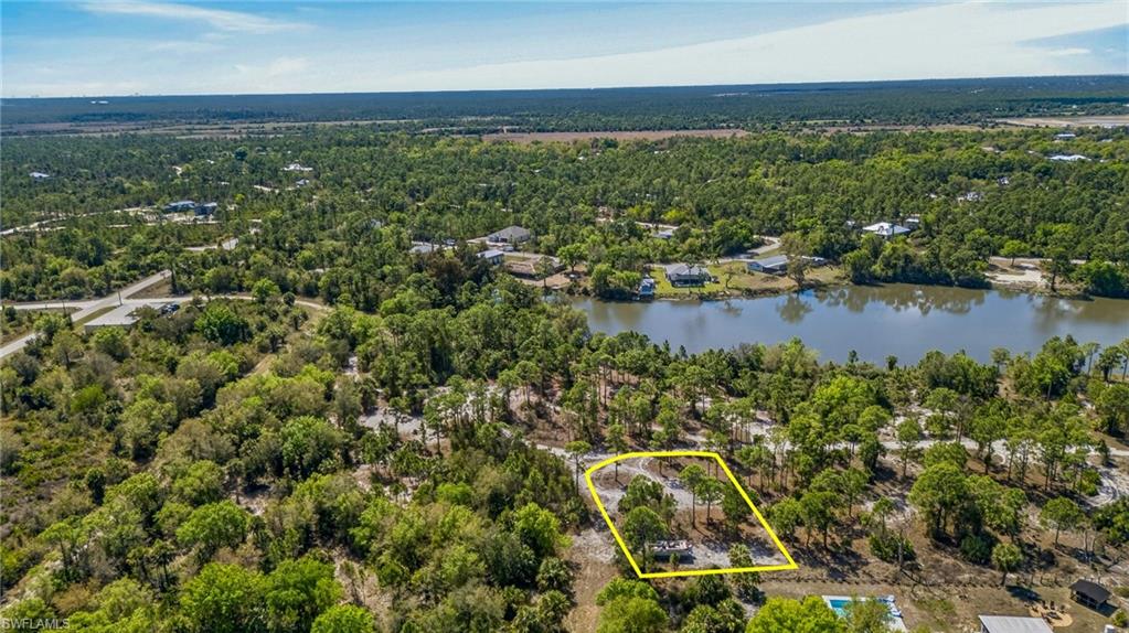Aerial view of property and surrounding area with property parcel outlined and a large body of water