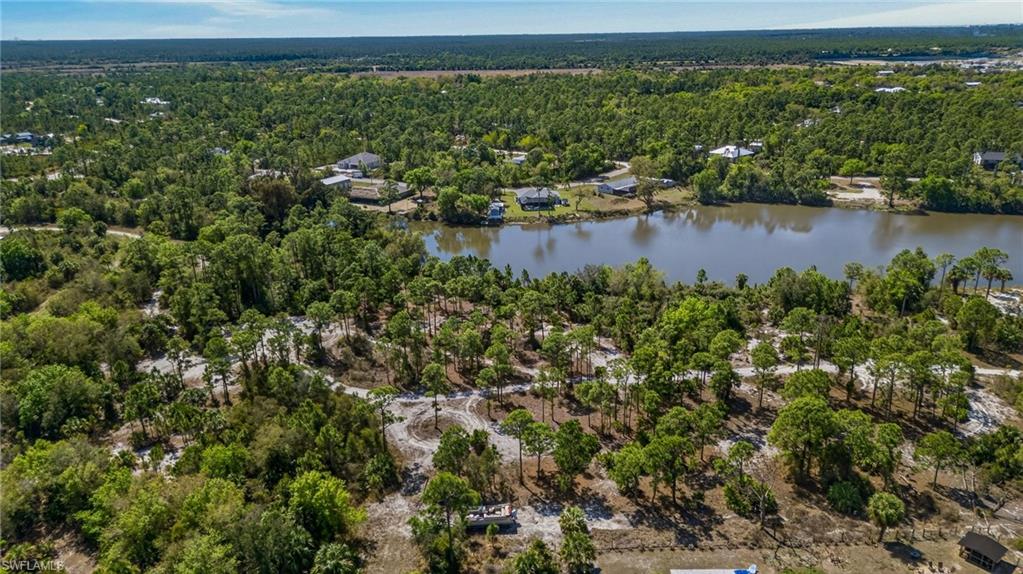 Drone / aerial view of a heavily wooded area and a nearby body of water