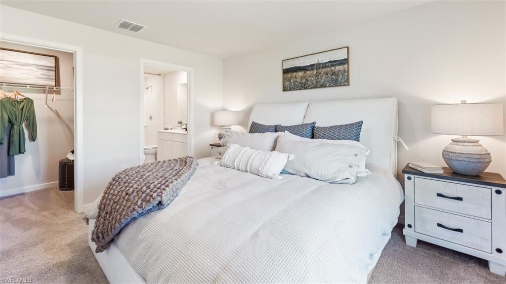 Model home. Bedroom with light carpet, a closet, and connected bathroom