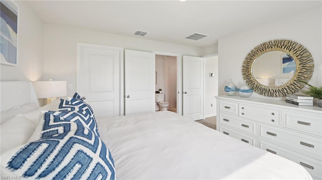 Model Home. This interior space features white walls, a white dresser with drawers, and a round mirror with a decorative frame
