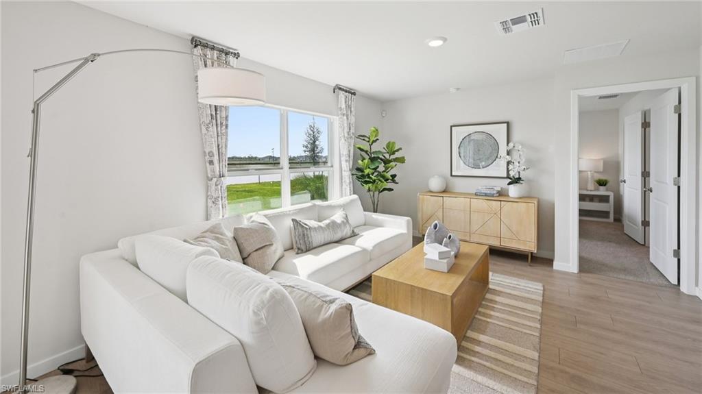 Model Home. The living area features light-toned walls, wood-style flooring, and a large window providing views of the exterior