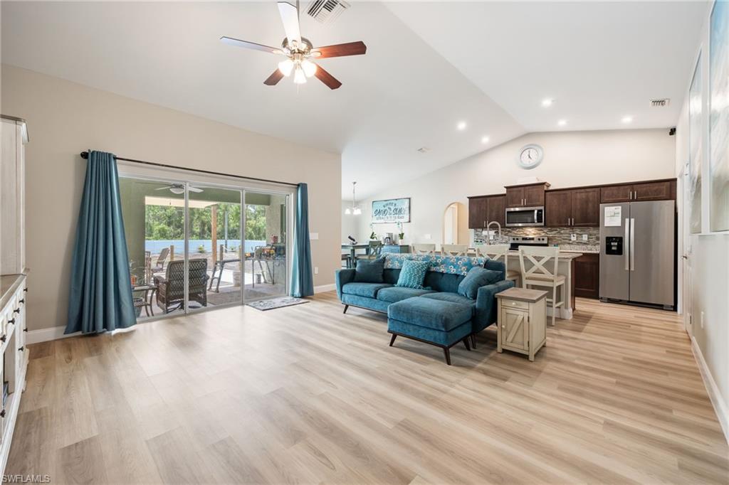 Vaulted ceiling living area featuring light wood-finish flooring, recessed lighting, and a ceiling fan
